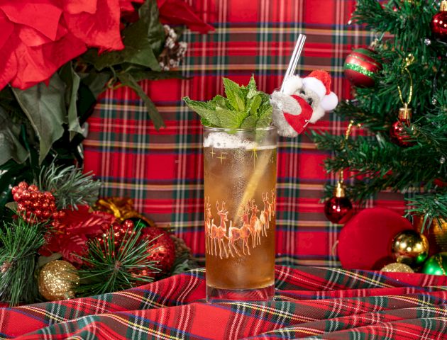 A festive holiday drink garnished with mint and a Santa hat stirrer, set amidst Christmas decorations.